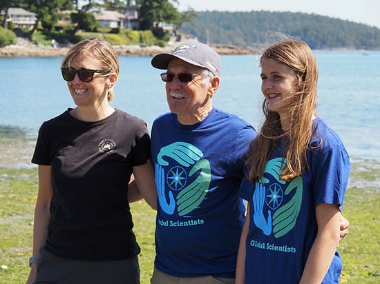 A three-generational family stands together on the shore after having completed a microplastics surey