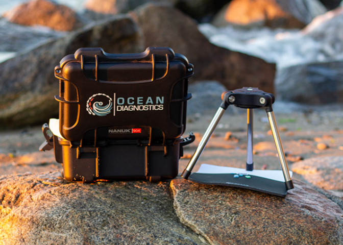 Microplastics analysis system and carrying case sit on a rock at the beach during sunset