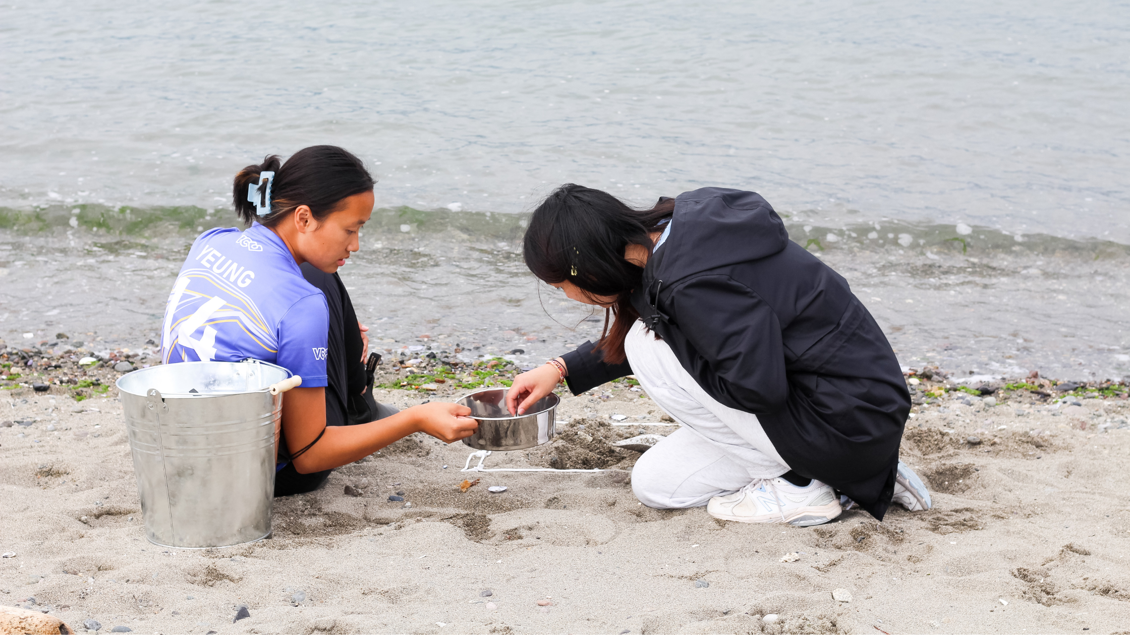 Pictured above Zoe conducts a microplastics survey at a Vancouver beach by sieving sand and picking out microplastic particles.