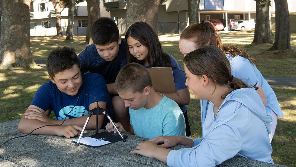 Six middle school-aged children gather around the Saturna Imaging System, classroom technology to analyze microplastics data.